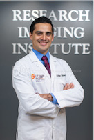 doctor posing in front of research imaging institute sign